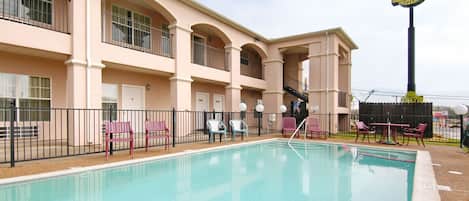 A hotel with a swimming pool, outdoor seating, and a sign for 'Super 8 Motel'.