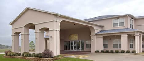 A building with a covered entrance, large windows, and a sign indicating it is a hospital.