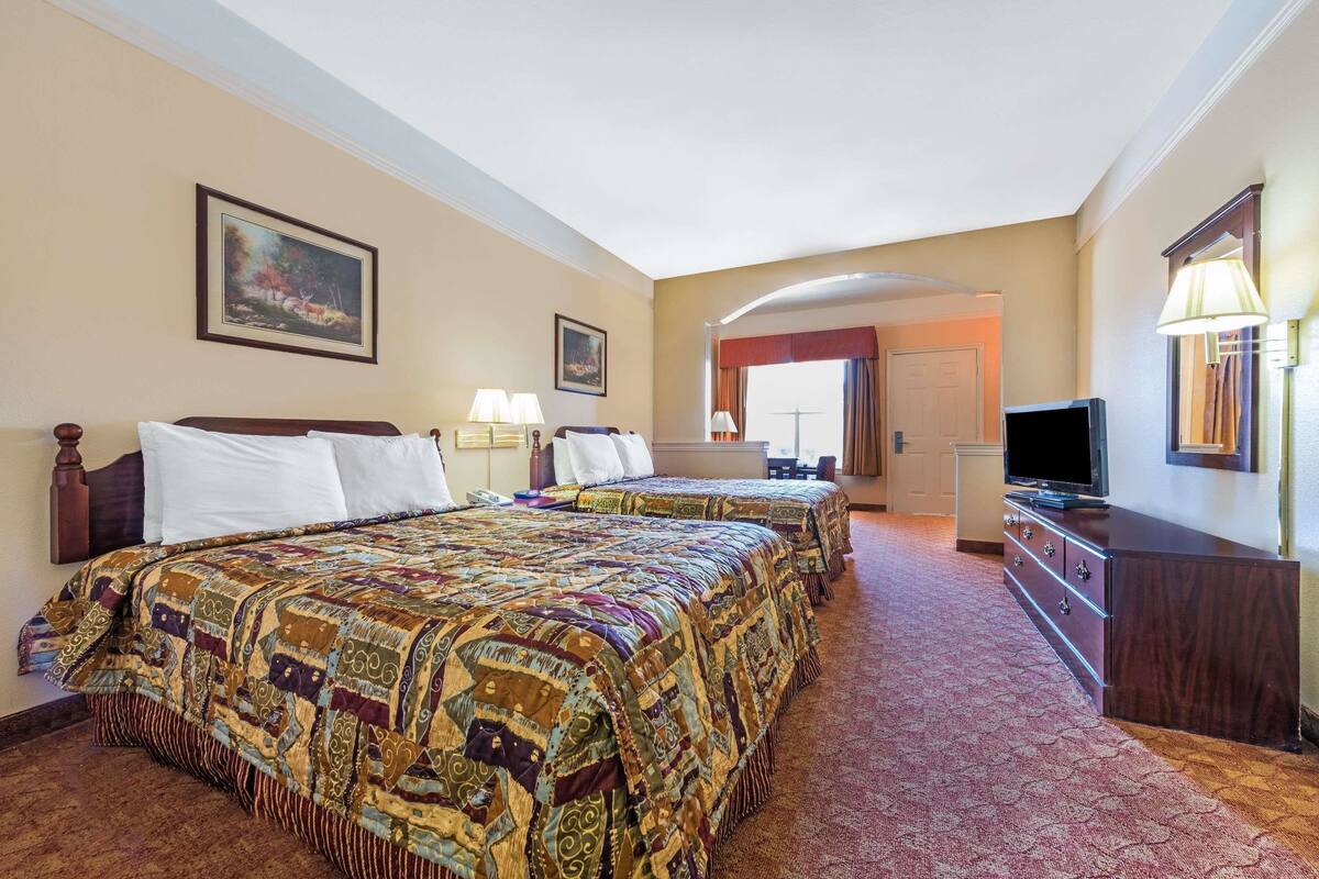 Une chambre d’hôtel avec deux lits, une télévision, une commode et un tableau au mur.