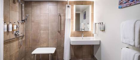 A modern bathroom with a shower, a sink, and a bench.