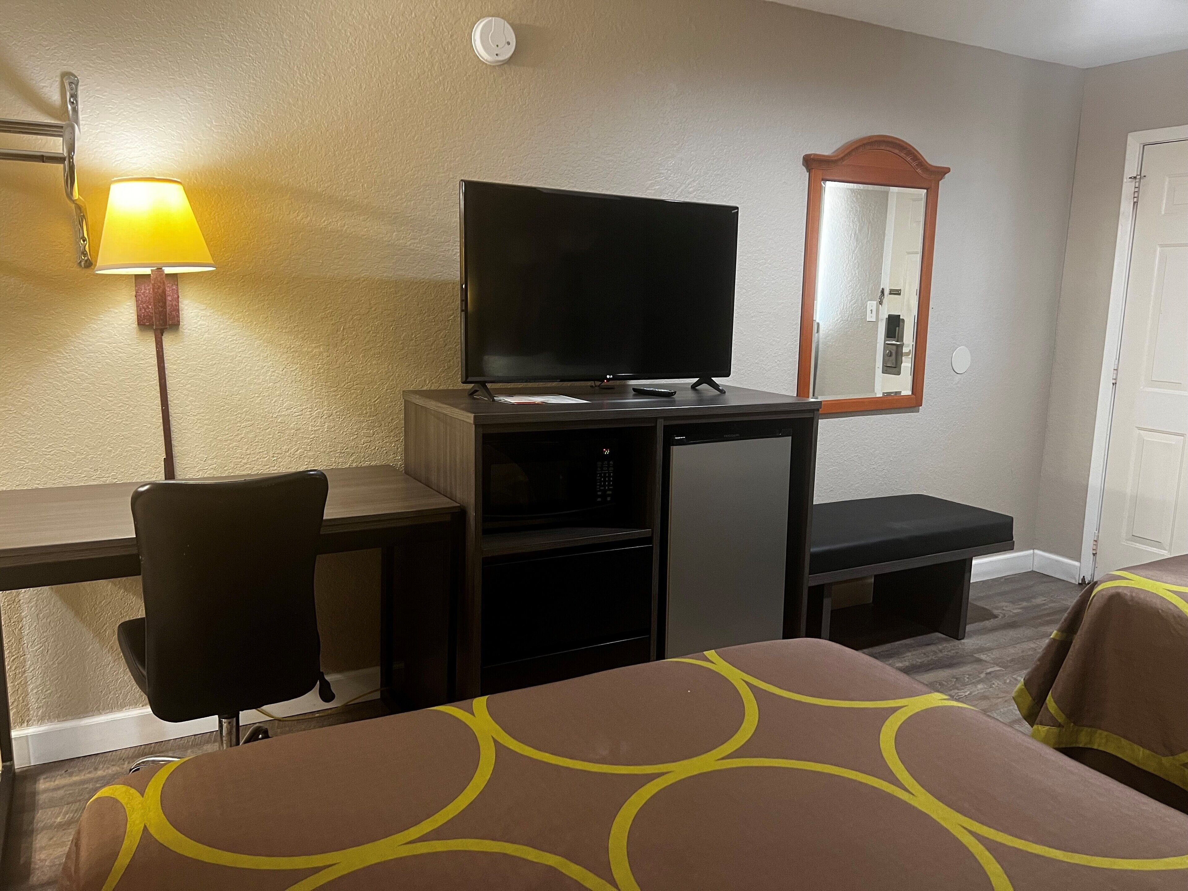 Une chambre d’hôtel comprenant un lit, un bureau avec une télévision, une chaise et une lampe.