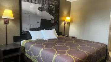 Habitación de hotel con una cama grande, dos mesitas de noche, dos lámparas y un cuadro grande en la pared.