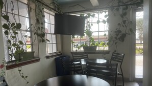 A room with a round table and chairs, a television mounted on the wall, and potted plants. - Super 8 by Wyndham La Marque TX/Texas City Area (La Marque)