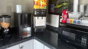 A coffee station with a coffee maker, a juice dispenser, and a microwave. - Super 8 by Wyndham La Marque TX/Texas City Area (La Marque)