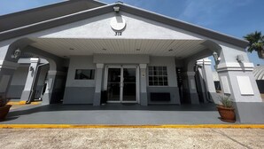 A building with a covered entrance, a number "312" above the door, and a potted plant to the right. - Super 8 by Wyndham La Marque TX/Texas City Area (La Marque)