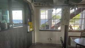 A restaurant interior with a counter, a window with a view of the outside, and a table with chairs. - Super 8 by Wyndham La Marque TX/Texas City Area (La Marque)