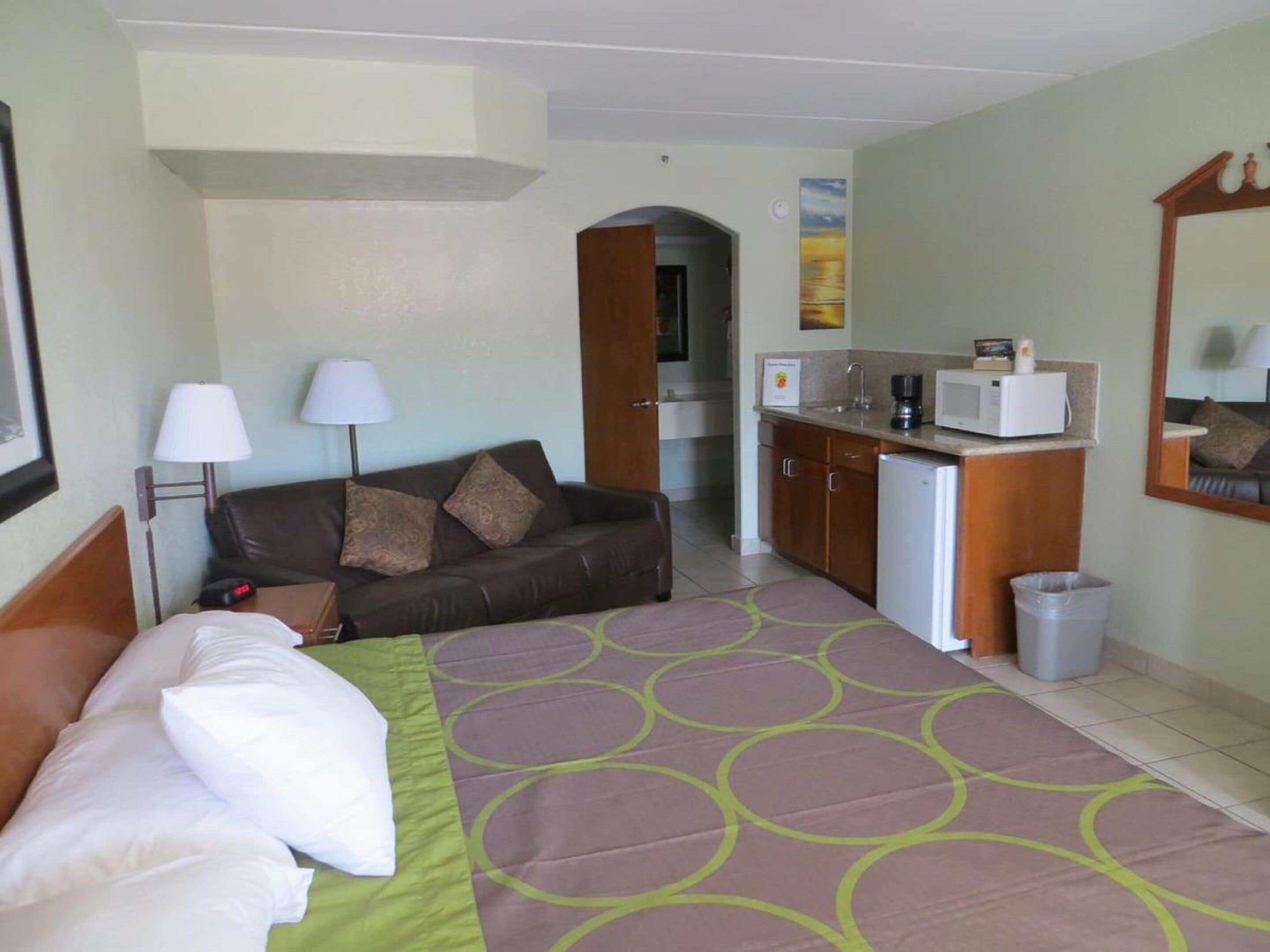Une chambre d’hôtel comprenant un lit, un canapé, une kitchenette et une salle de bain.