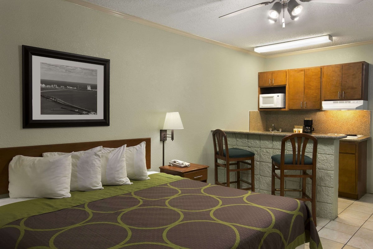 Une chambre d’hôtel équipée d’un lit, d’un bureau avec une chaise, d’un four à micro-ondes et d’un petit coin cuisine.
