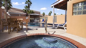 A pool area with a hot tub, lounge chairs, and a covered seating area. - Super 8 by Wyndham South Padre Island (South Padre Island)