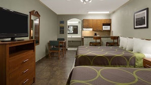 A hotel room with a bed, a TV, a desk, a chair, and a kitchenette. - Super 8 by Wyndham South Padre Island (South Padre Island)