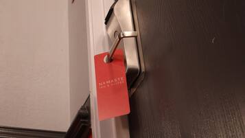 Una puerta con un picaporte metálico y una tarjeta roja adherida.