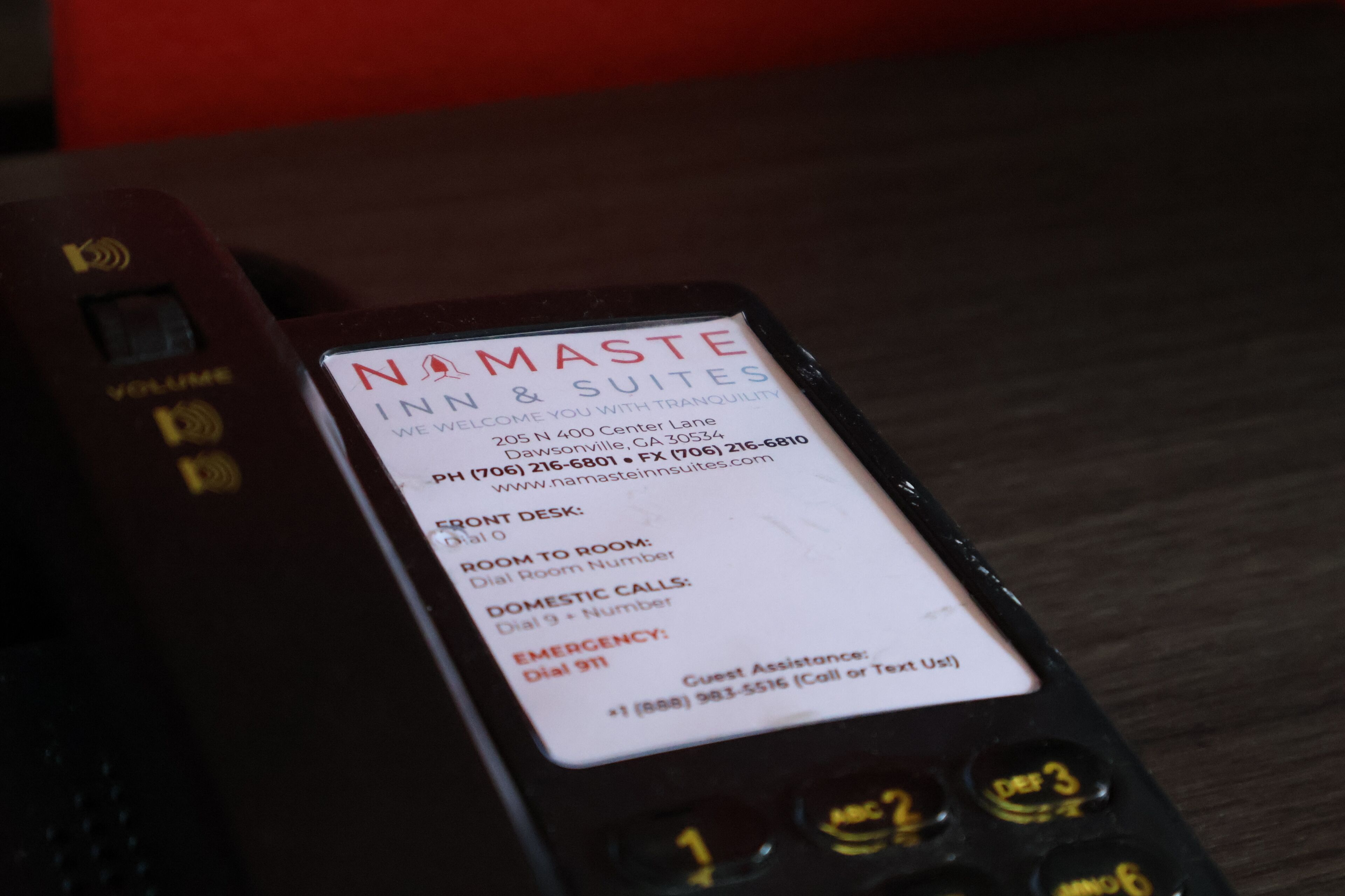 A hotel phone with a label listing amenities like front desk, room to room, domestic calls, and emergency contact information.