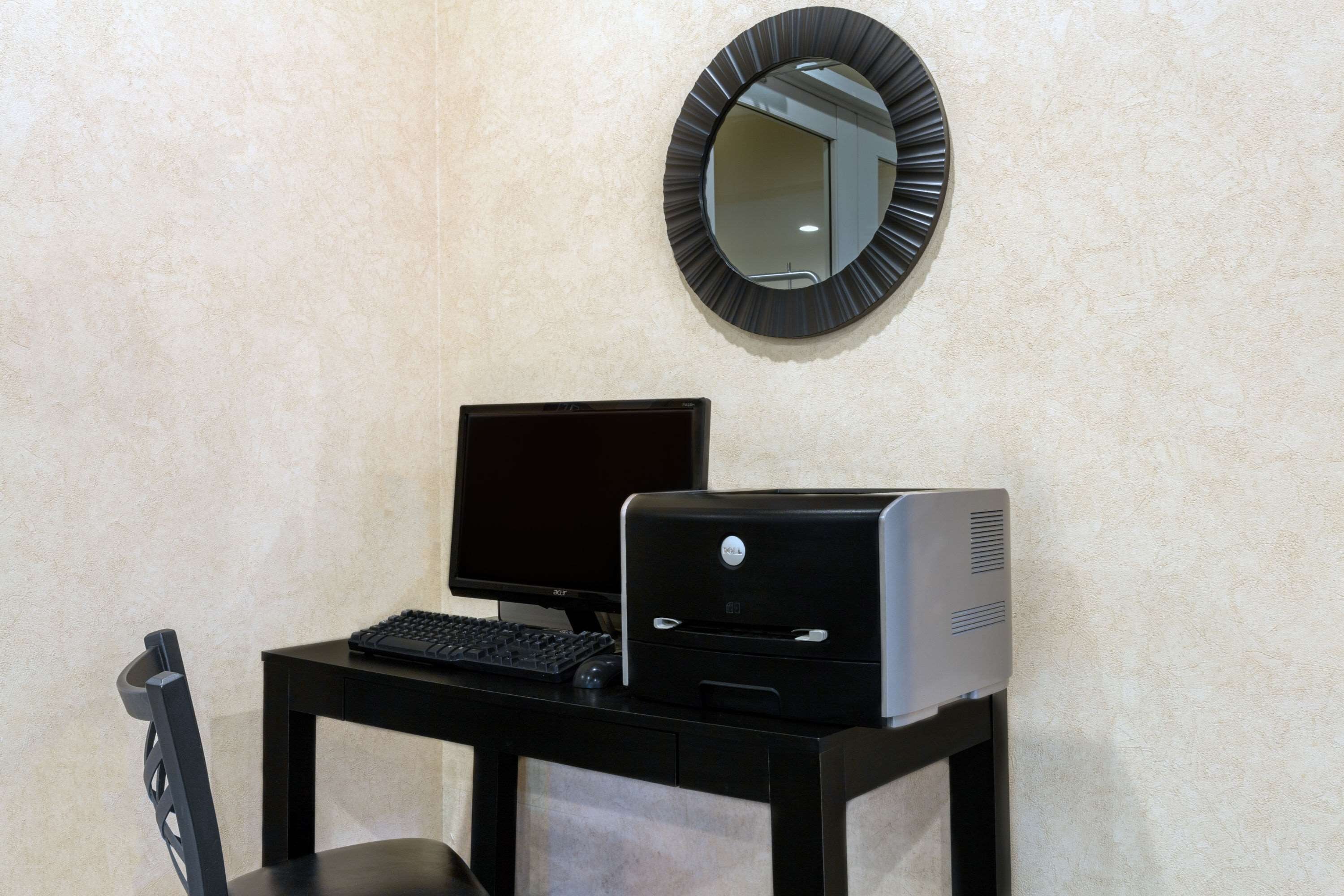 A computer desk with a monitor, keyboard, and printer.