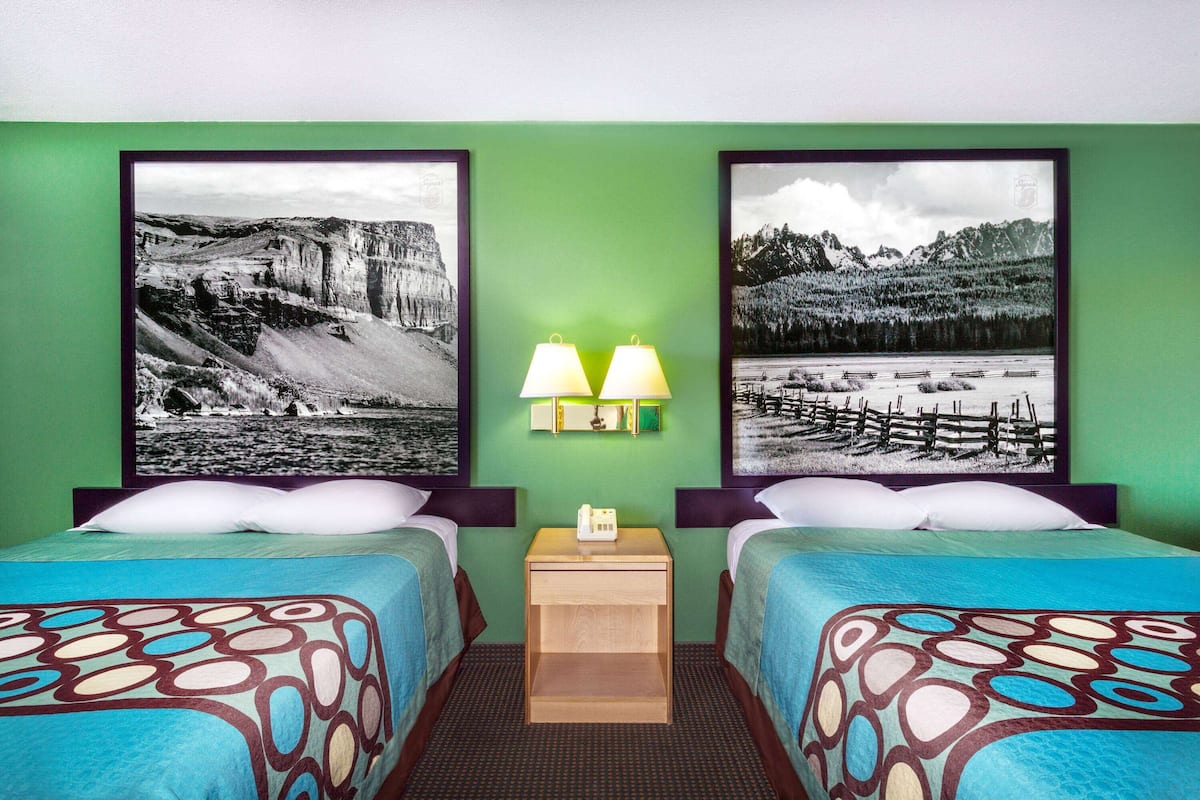 Een hotelkamer met twee bedden, groene wanden en twee grote zwart-witfoto's.
