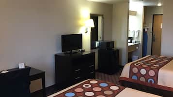 A hotel room with two beds, a desk, a dresser, a television, and a mirror.