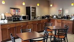 A restaurant with a counter, seating area, and kitchen appliances.