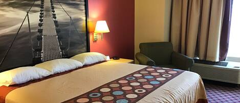 A hotel room with a large bed, a chair, a wall-mounted lamp, and a window with curtains.