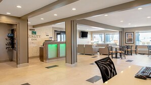 Vestíbulo de hotel con mostrador de recepción, zona de estar y televisor.