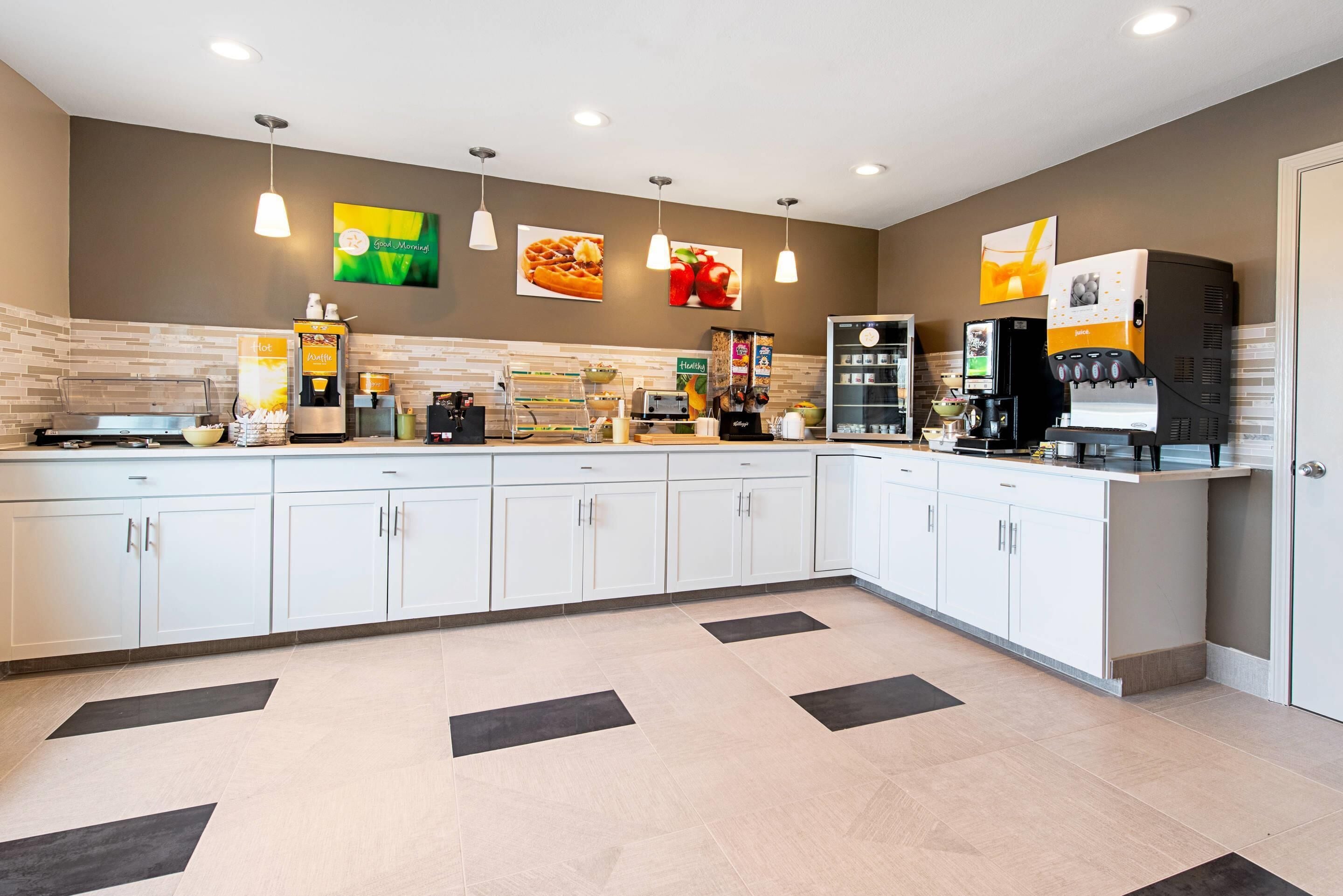 A modern kitchen with white cabinets, a coffee machine, and a waffle maker.