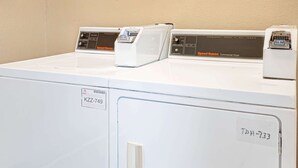 Een rij witte commerciële drogers, elk met bedieningspaneel en een uniek identificatienummer.
