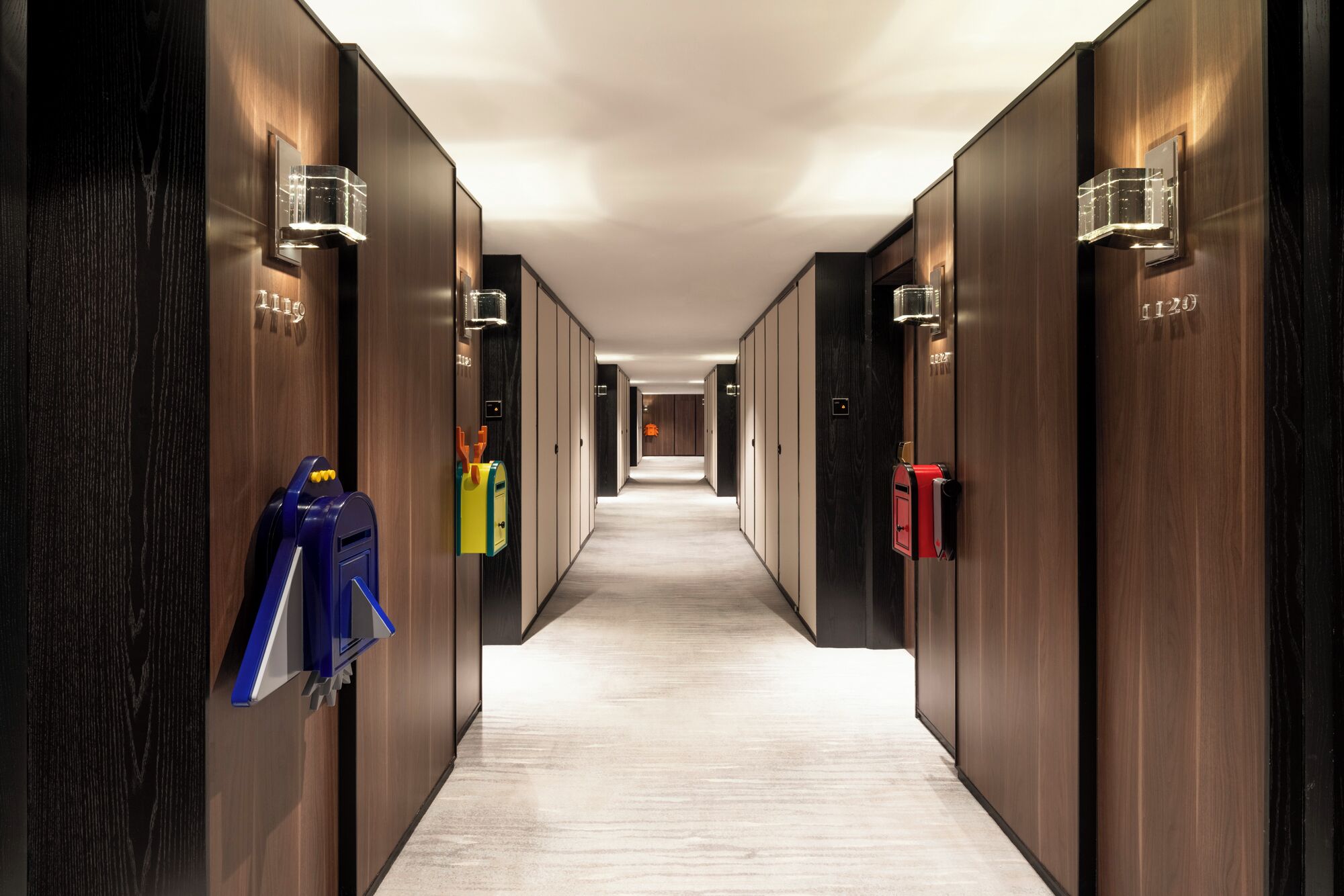 A hotel corridor with wooden walls, mail slots, and a lighted path.