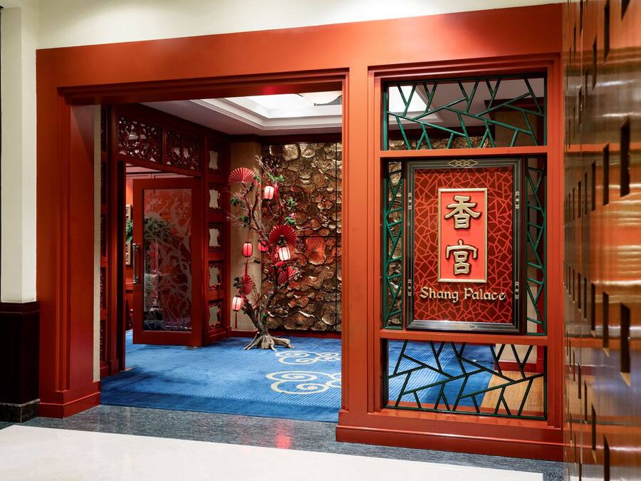 A traditional Chinese architectural entrance with a red door, a blue carpet with white patterns, and a sign reading "Shang Palace".