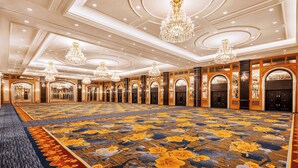 A large, well-lit room with multiple chandeliers, a patterned carpet, and a series of doors leading to other areas. - Shangri-La Harbin (Harbin)