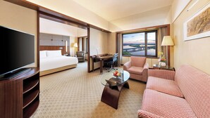 A hotel room with a bed, a desk, a television, a sofa, and a large window with a view. - Shangri-La Harbin (Harbin)