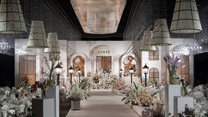 A wedding venue with a central aisle, floral arrangements, and chandeliers.
