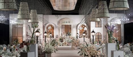 Un lieu de réception pour mariages doté d’une allée centrale, de compositions florales et de lustres.
