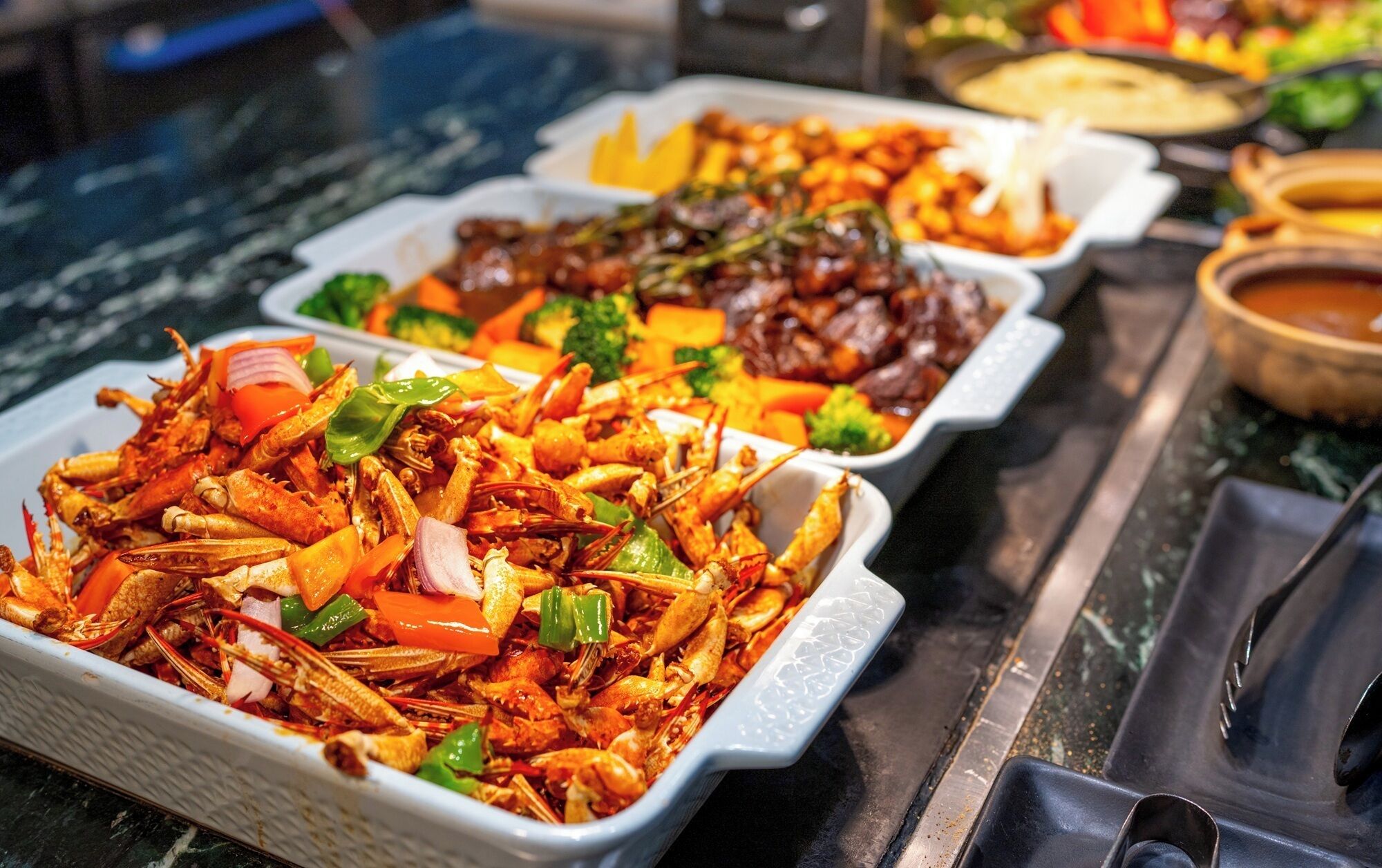 A buffet with various dishes including seafood, vegetables, and meat.