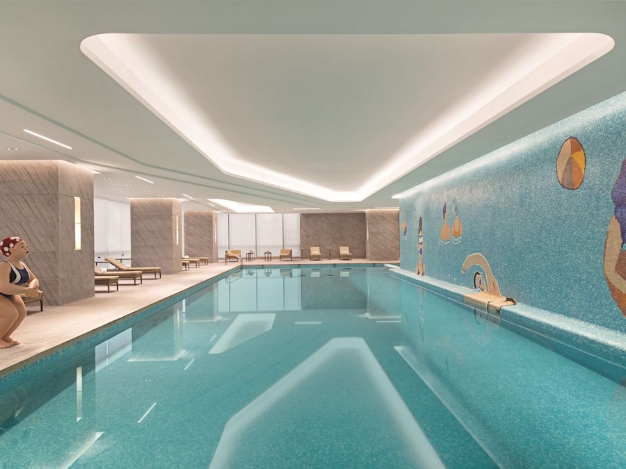 Une piscine intérieure moderne offrant une vue dégagée sur l’espace piscine, les chaises longues et une fresque murale.