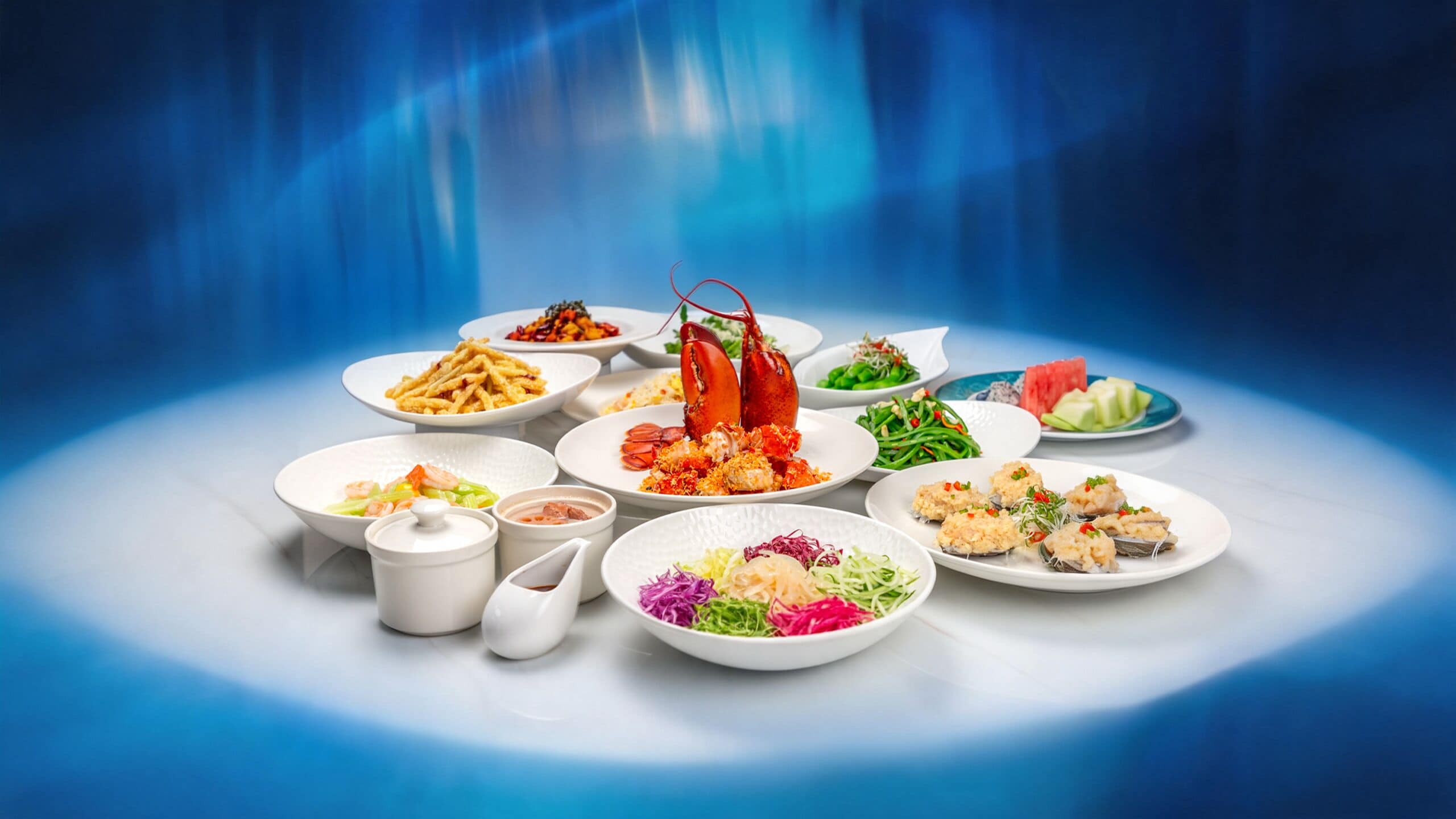 A variety of dishes including seafood, vegetables, and a lobster, arranged on a table against a blue background.