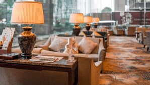Un vestíbulo de hotel con un conjunto de sofás, lámparas y un florero sobre una mesa.
