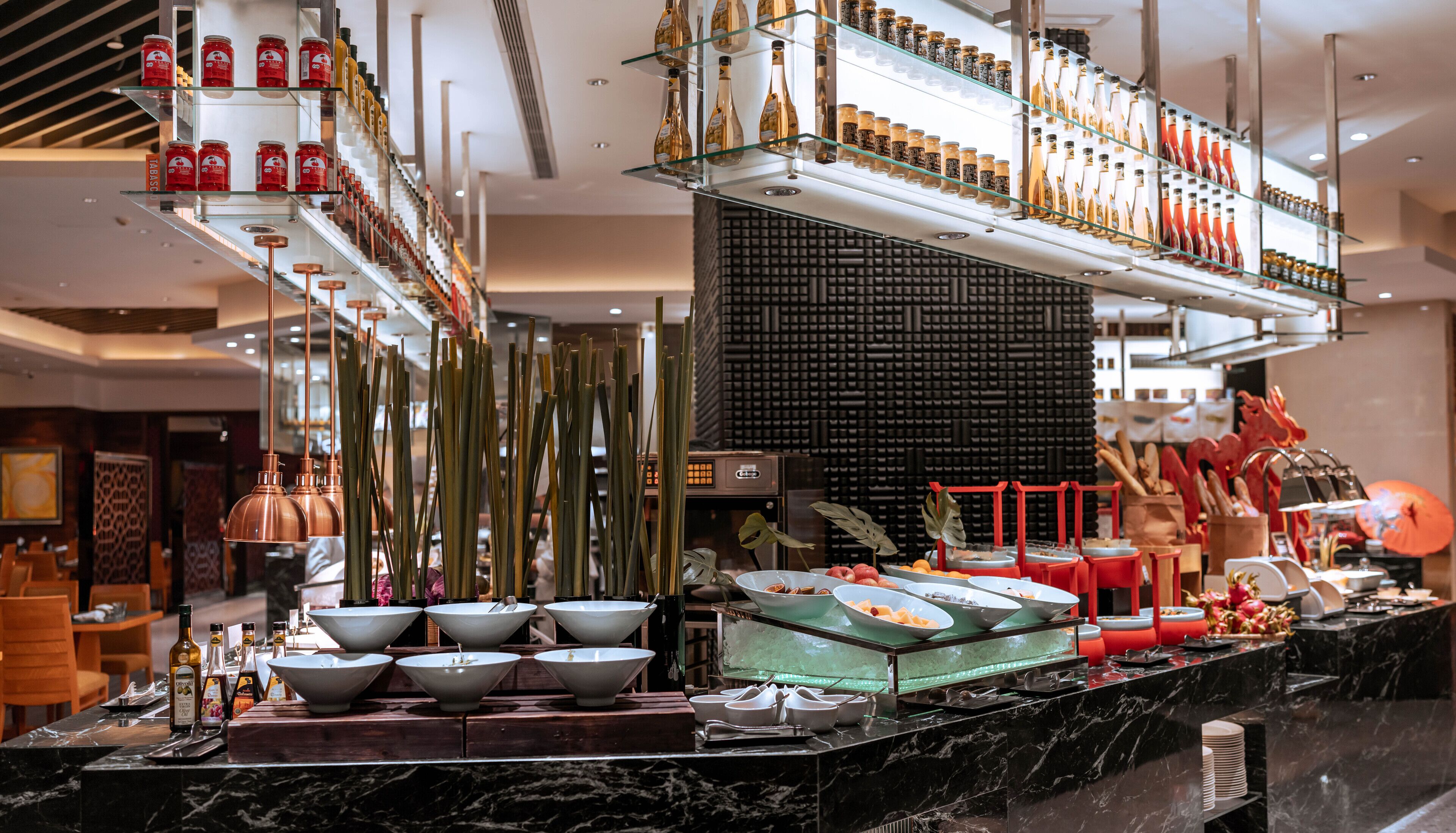 A well-lit hotel lobby with a reception desk, a seating area, and a buffet setup.