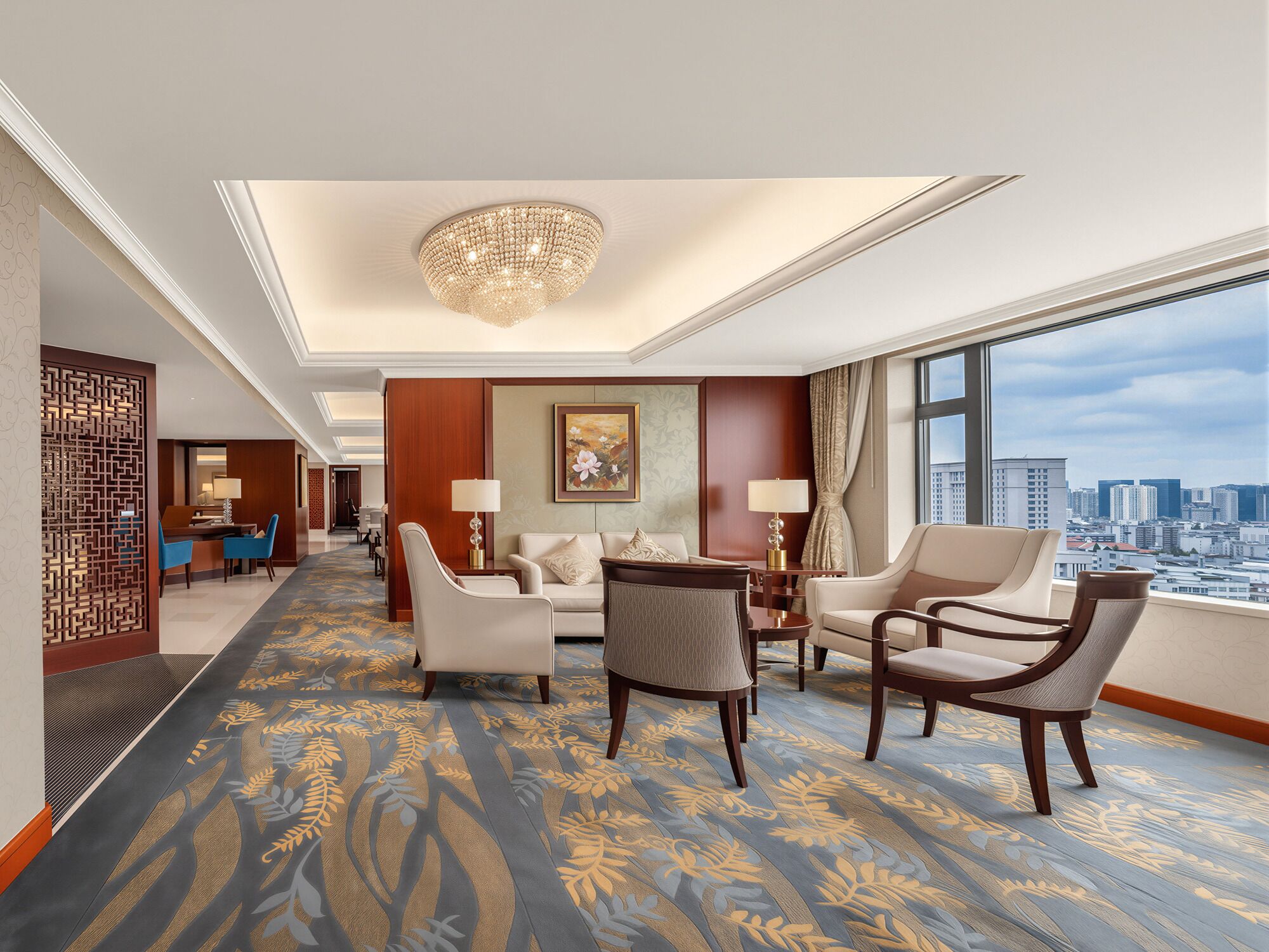A hotel room with a city view, a chandelier, a patterned carpet, and a dining area.