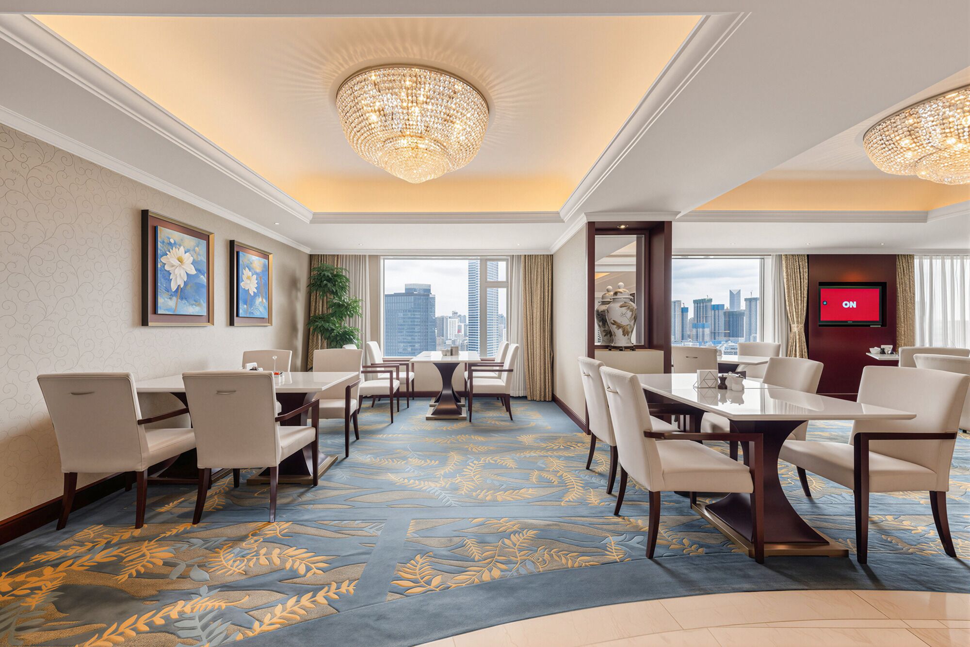 Salón de conferencias de hotel con vista a la ciudad, candelabros grandes y diseño moderno.