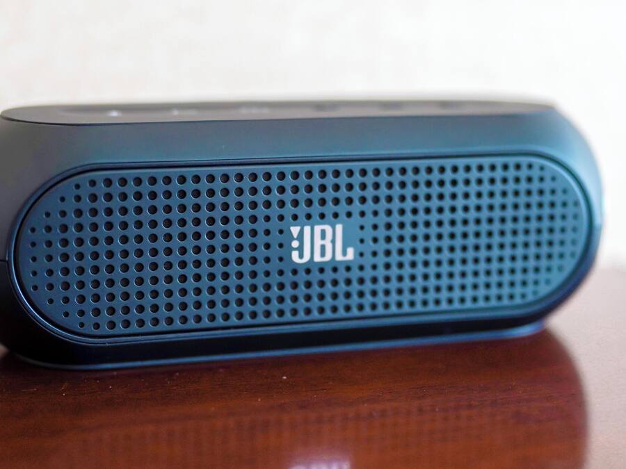 Un altavoz portátil JBL sobre una superficie de madera.