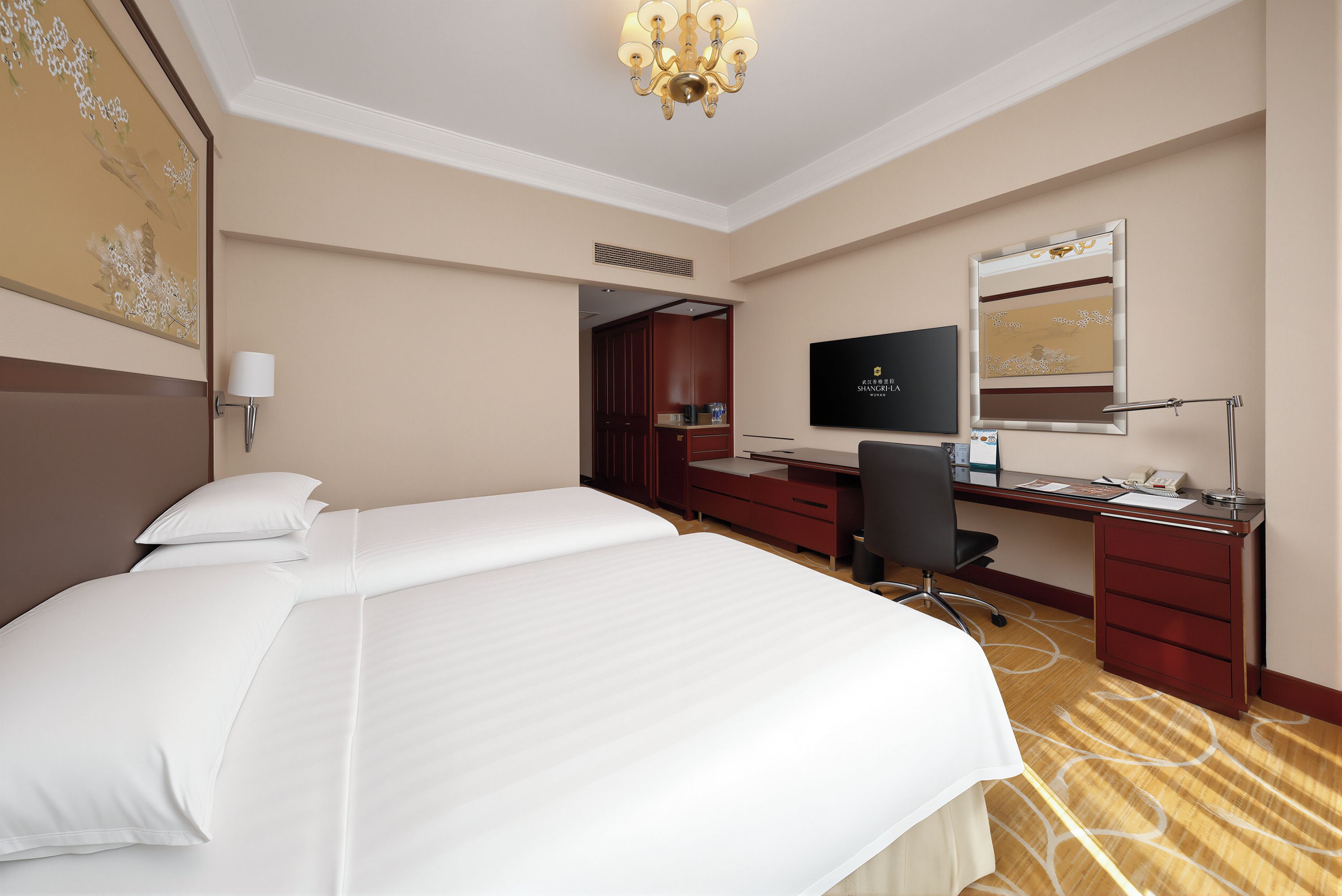 A hotel room with a large bed, a desk with a computer, a television, and a mirror.