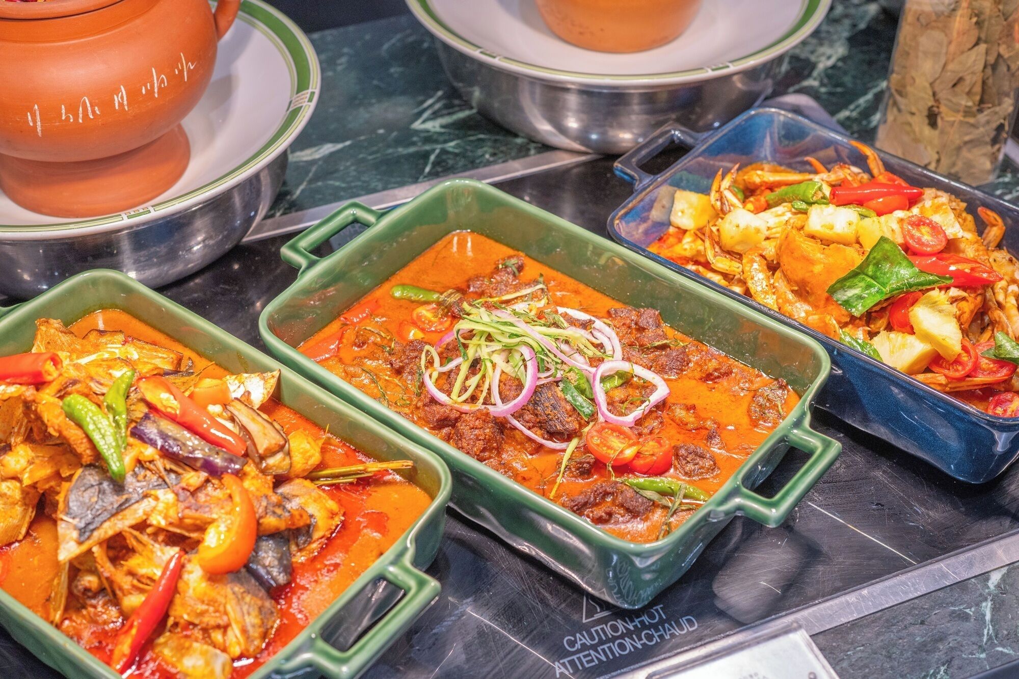 A buffet with various dishes, including seafood and vegetables, served in green serving dishes.