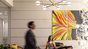 Un vestíbulo moderno con un cuadro abstracto de gran tamaño, una araña y una zona de estar con una mesa de centro.