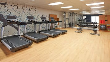 A gym with treadmills, weight machines, and a mirrored wall.