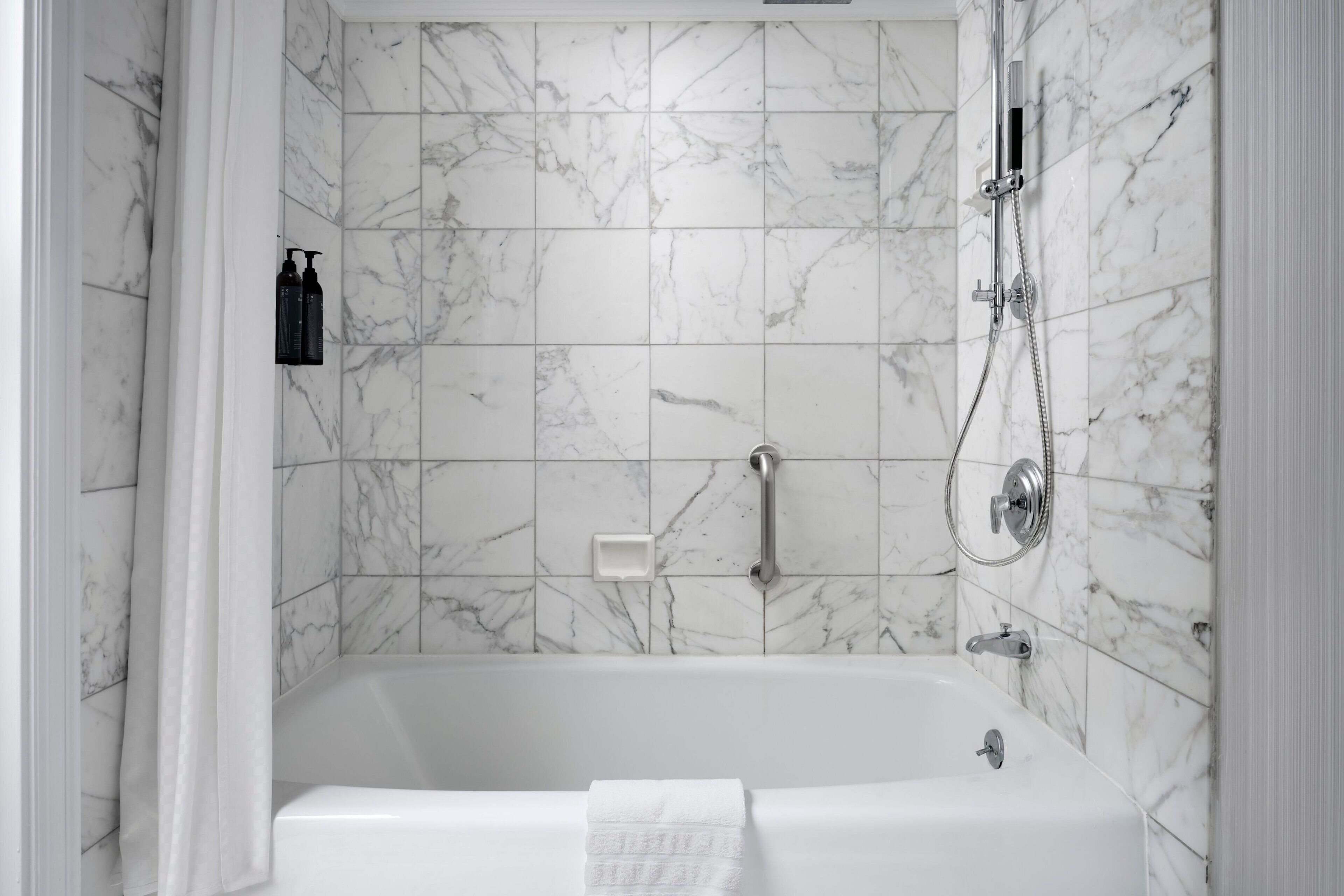 Une salle de bain moderne avec une douche carrelée en marbre et une baignoire.