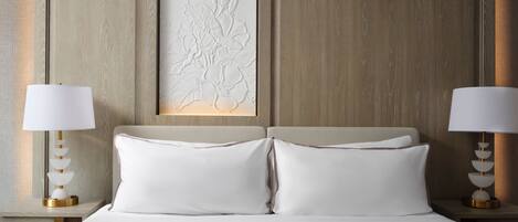 A neatly made bed with white linens and two bedside lamps.