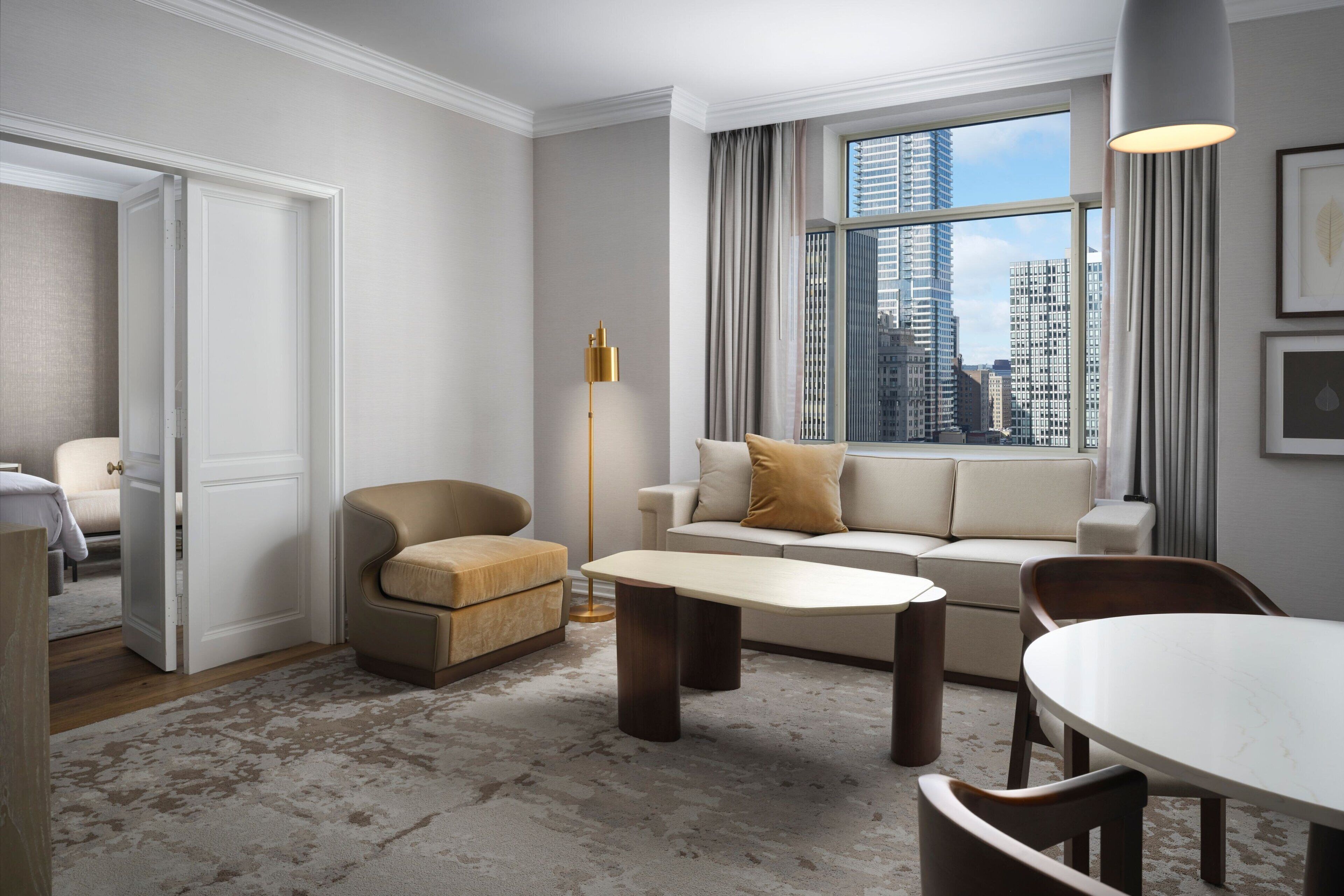 A modern living room with a sofa, armchair, coffee table, and dining table.