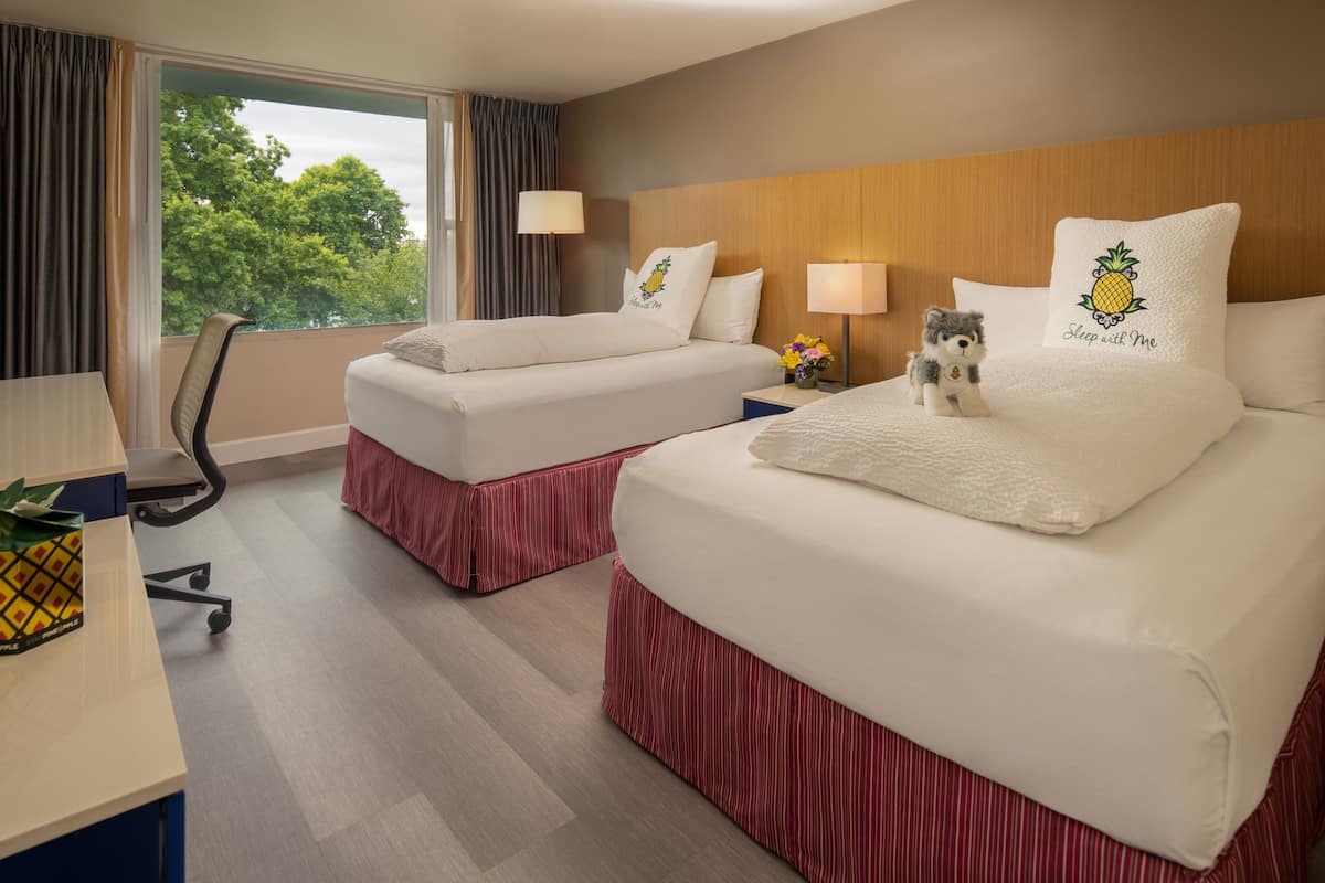 A hotel room with two beds, a desk, and a chair.