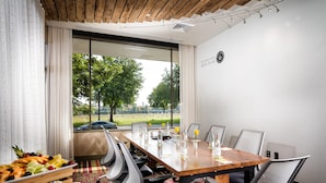 A conference room with a wooden table, chairs, and a buffet table with fruit and pastries. - Staypineapple, Hotel Rose, Downtown Portland (Portland)