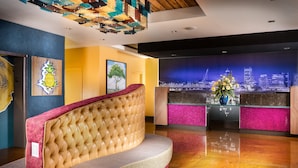 A modern reception area with a curved sofa, a cityscape mural, and a decorative pineapple artwork. - Staypineapple, Hotel Rose, Downtown Portland (Portland)