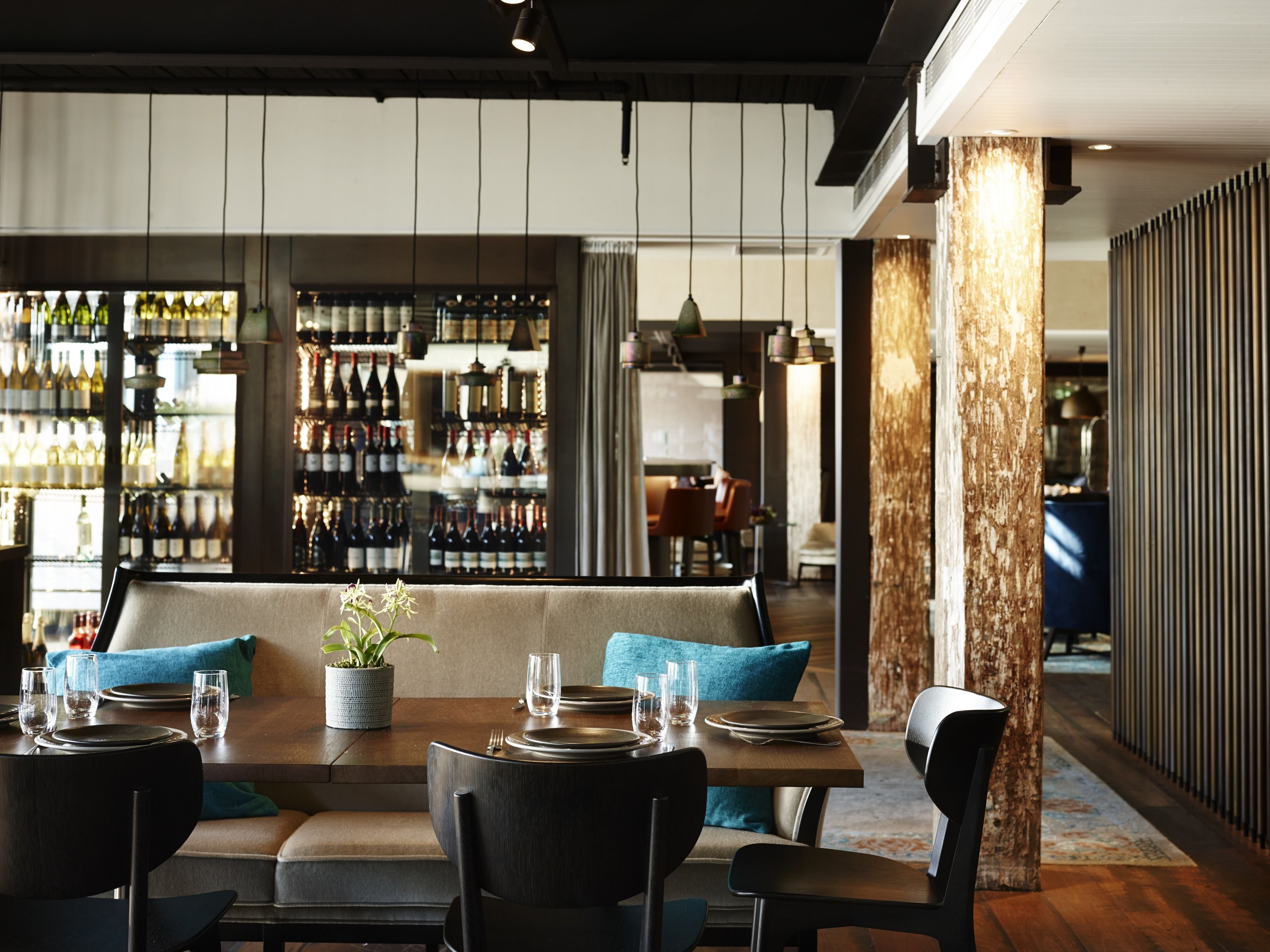 A restaurant with a bar area, wooden tables, and chairs.