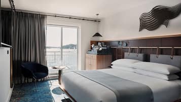 Habitació d'hotel amb un llit gran, una taula de treball amb cadira, vista al mar i un element decoratiu a la paret.